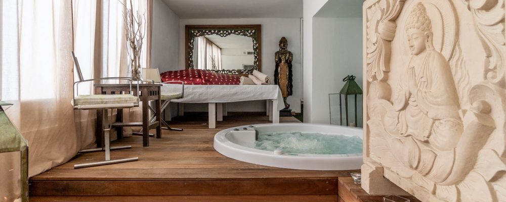 Sala relax con letto, jacuzzi e decorazioni orientali.
